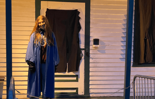 Jeune fille déguisée derrière maison décorée halloween.