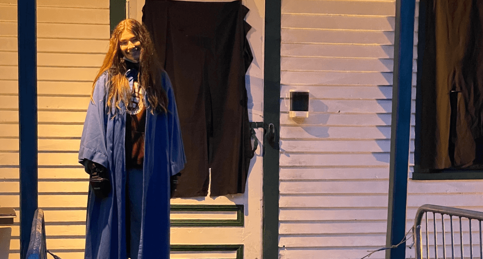 jeune fille déguisée derrière maison décorée halloween.